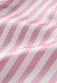 Pamut szövet váltakozó rózsaszín és fehér csíkokkal, sima tapintású és hullámos eséssel, kiemelve a minta egységességét.
