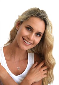 Sølv halskæde med en rund vedhæng, der har klare sten, båret over en hvid ærmeløs top. Modellen har langt bølget blond hår.