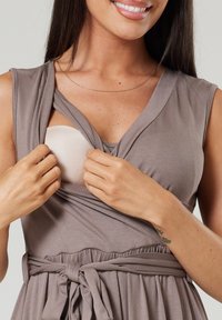 Wrap dress in taupe fabric with a v-neck and gathered waist, showcasing a beige bra insert being revealed by a model's hands.