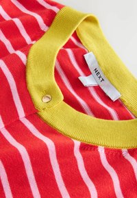 Rot- und rosafarbener gestreifter Pullover mit einem gelben Rippkragen und einem goldenen Knopfdetail am Halsauschnitt. Markenlabel sichtbar.