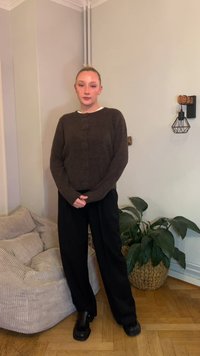 Brun yllekofta med knappar, kombinerad med svarta vida byxor och svarta skor. Mjuk textur och avslappnad passform, mot en ljus bakgrund.