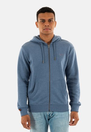 Blauwe rits hoodie van zachte stof, met een rits aan de voorkant, twee zakken en een trekkoord op de capuchon. Ribbelmanchetten ronden het ontwerp af.