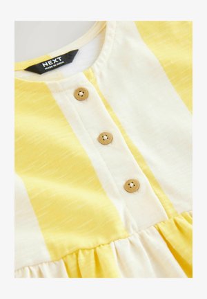Žluté a bílé pruhované šaty s kulatým výstřihem, zdobené třemi dřevěnými knoflíky a nařasenou sukní. Vyrobeno z měkké, lehké látky.