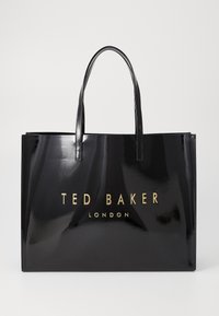 Saco tote preto brilhante com alças duplas e lettering dourado "TED BAKER LONDON" na frente. Forma retangular, textura suave.