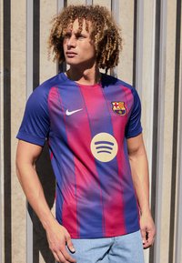 Tricou FC Barcelona cu dungi albastre și maronii, logo-ul sferic Spotify pe față, mâneci scurte și decolteu rotund.