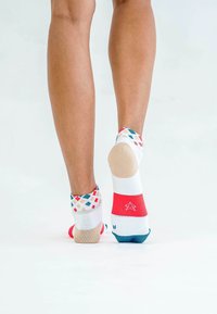 Bunte Knöchelsocken mit einem weißen Grundton und roten, blauen sowie gemusterten Akzenten. Texturierte Fersen- und Zehenbereiche erhöhen den Grip und den Komfort.