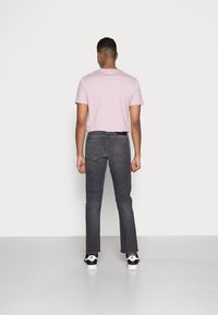 Camiseta de manga corta rosa, jeans gris ajustados, zapatillas negras. El conjunto presenta un corte relajado y un diseño clásico con detalles mínimos.