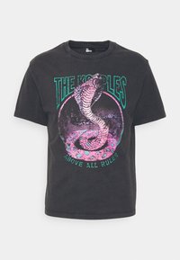 Camiseta de algodón negra con un gráfico colorido de una serpiente enroscada, con el texto "LOS KOUPLES" y "SOBRE TODAS LAS REGLAS" en letras negritas.