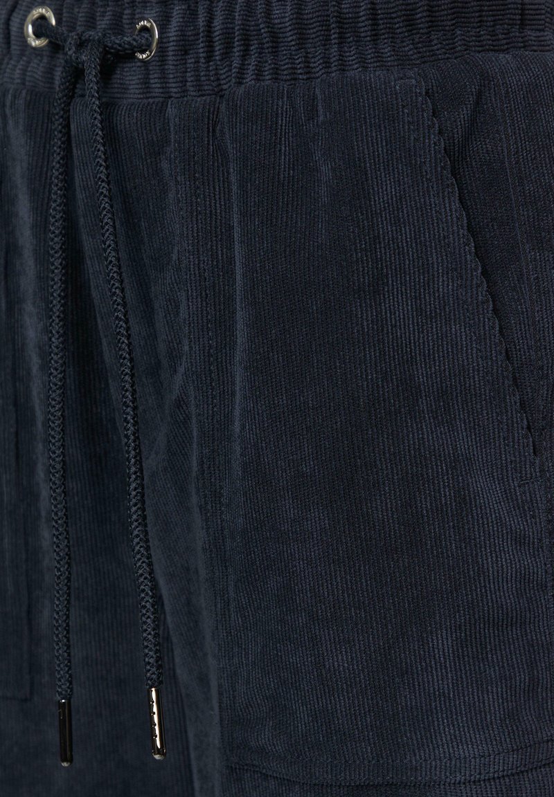 Shorts en velours côtelé bleu marine avec une taille élastique, dotés d'un cordon de serrage, de poches latérales et de côtes texturées verticales.