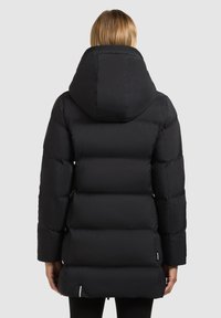 Fekete steppelt kapucnis dzseki, gumis mandzsettákkal. A hátsó nézet középhosszú szabást és logós címkét mutat.