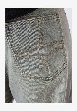 Een dennenjeanszak met een stervormig gestikt ontwerp in lichtblauwe stof, afgewerkt met contrasterende tan draad en een gestructureerd oppervlak.