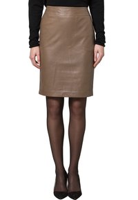 Jupe crayon en cuir marron avec une texture lisse et un design long jusqu'aux genoux. Dispose d'une taille haute et est stylisée avec des collants noirs et des chaussures.