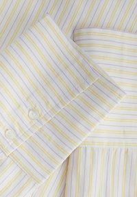 Chemise en coton rayée avec des rayures jaunes et lavande réparties de manière uniforme sur un fond blanc ; comprend deux boutons blancs et des coutures soignées.