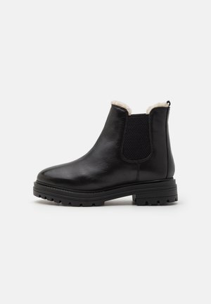 Bottines en cuir noir avec un panneau latéral élastique texturé, une doublure en fausse fourrure et une semelle robuste pour une bonne traction. Design classique Chelsea.