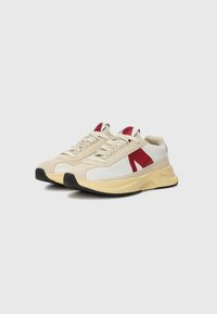 Sneakers with a beige suede and white fabric upper, red accents, and a black rubber sole, featuring a textured and cushioned design.