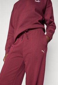 Burgundia sweatshirt ja lõngadest komplekt, mis on valmistatud pehmest kangast. Omab väikest valget Puma logo ja reguleeritava nööriga detaili pükstel.
