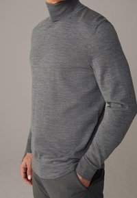 Grauer Rollkragenpullover mit langen Ärmeln, aus einem weichen Material gefertigt. Verfügt über gerippte Bündchen und eine glatte Textur.