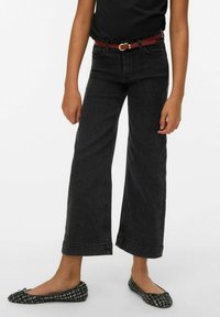 Svart jeans med vida ben och hög midja, tillverkade av denim, med fem fickor och kontrastsömmar, kombinerade med svarta mönstrade flatskor.