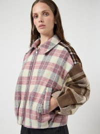 Srajca z volneno karo tkanino v nežnih roza, krem in rjavih odtenkih. Ima zadrgo, velik ovratnik in kontrastne rokave z vzorcem.