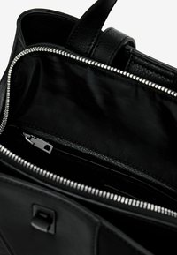 Innenansicht einer schwarzen Lederhandtasche mit glatter Textur; verfügt über einen silbernen Reißverschluss, eine Reißverschlusstasche und ein minimalistisches Design.