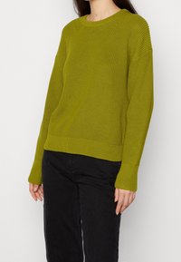 Grüner gerippter Strickpullover mit Rundhalsausschnitt, überschnittenen Schultern und langen Ärmeln. Hat einen strukturierten Stoff und eine lockere Passform.