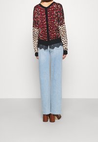 Maglione multicolore con motivi floreali e stampa leopardata, rifinito con un orlo in pizzo, abbinato a jeans a vita alta di un blu chiaro e tacchi marroni.