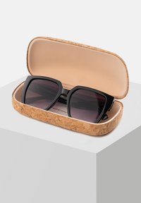 Czarne, oversize okulary przeciwsłoneczne z gradientowymi soczewkami w korkowej, twardej etui, z gładkim beżowym wnętrzem.