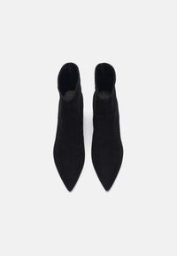 Bottines en daim noir avec un design à bout pointu, présentant une texture lisse et une silhouette épurée. Pas de quincaillerie ou d'ornement visible.