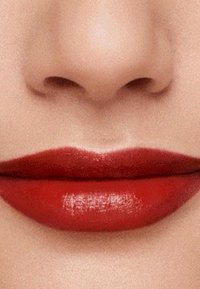 Red lipstick applied smoothly on full lips, with a glossy finish. The surrounding skin is light-toned, emphasizing the lip color contrast.