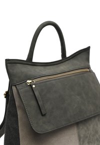 Zaino in pelle grigia con parte superiore arrotondata e tasca con zip frontale. Presenta hardware dorato e una combinazione di finiture lisce e testurizzate.