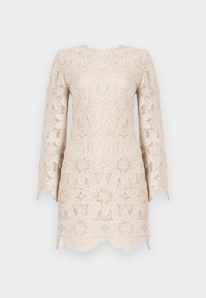 Pitkähihaista pitsimekkoa vaaleanbeige sävyssä, jossa on kukkakuosisia yksityiskohtia ja aaltoileva helma teksturoidulla pinnalla.