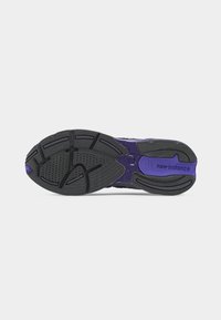 Semelle de chaussure New Balance noire et violette avec un motif de bande de roulement texturé et le nom de la marque visible sur la zone du talon.