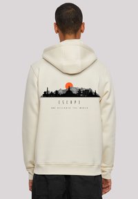 Cremefarbener Hoodie mit einem Grafikdesign einer Sunset über einer Bergsilhouette und dem Text "ESCAP3 AND DISCOVER THE WORLD" in Schwarz.