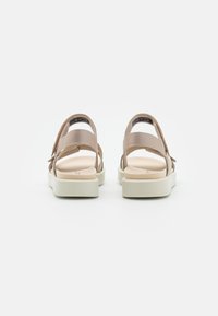 Beige sandaler med åpne remmer, polstrede såler og en hvit plattform. Teksturert stoffdetaljer på remmene gir kontrast.