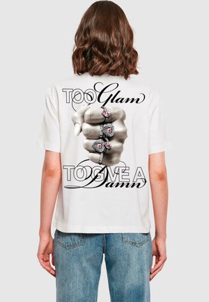 Witte katoenen t-shirt met een grafische print van een vuist versierd met ringen. De tekst luidt "TE veel glam om me iets te interesseren" in dikke letters.
