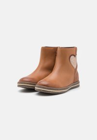 Bottines en cuir marron avec un accent cœur brillant, une tige texturée et une semelle empilée. Dotées d'une fermeture éclair sur le côté pour un enfilage facile.