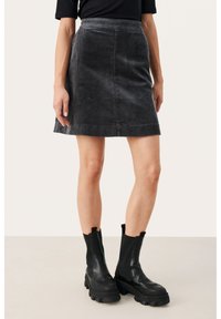 Mini-jupe en velours côtelé gris avec une silhouette �évasée. Assortie avec des bottes de cheville noires à semelle épaisse. Texture lisse et motif légèrement côtelé.