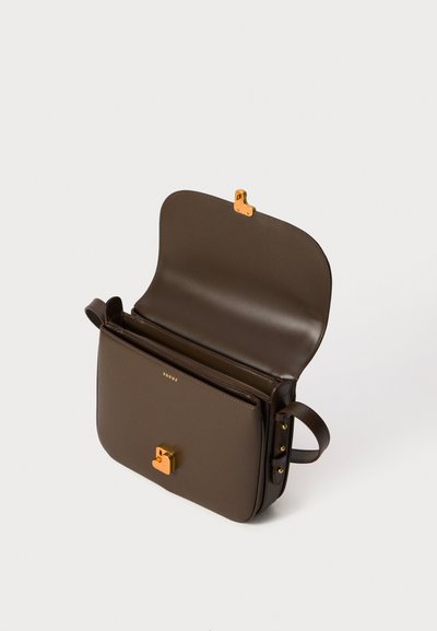 Sac à bandoulière en cuir marron avec fermoir doré et logo "soeur", rabat ouvert montrant des compartiments intérieurs divisés, sur fond blanc uni.