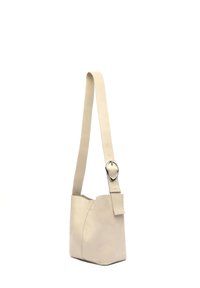 Borsa a spalla in pelle beige con design affusolato, texture liscia e una tracolla larga con una fibbia a forma di cuore in tonalità argento.