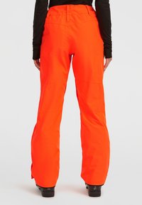 Feloranje skibroek met een gladde, waterdichte textuur, een brede pijpontwerp en een verstelbare tailleband. Versterkte zoom en stiknaden zichtbaar.