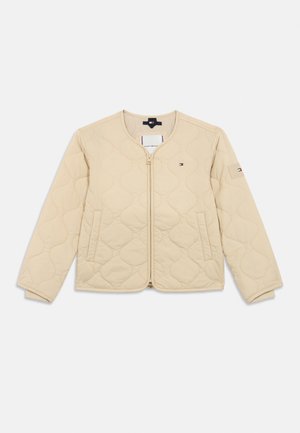 Beige steppelt kabát kerek nyakkal, elöl cipzárral, két oldalsó zsebbel és kis Tommy Hilfiger logókkal a mellkason és az ujjon.