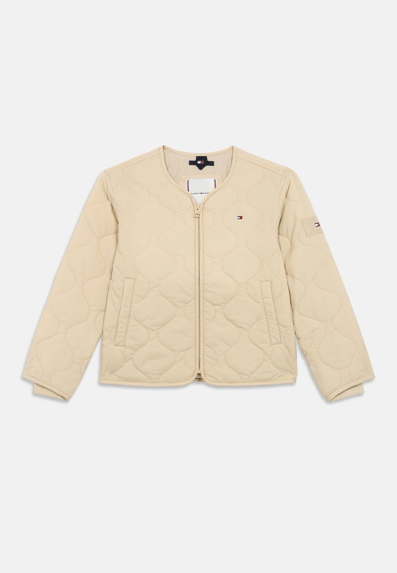 Beige steppelt kabát kerek nyakkal, elöl cipzárral, két oldalsó zsebbel és kis Tommy Hilfiger logókkal a mellkason és az ujjon.