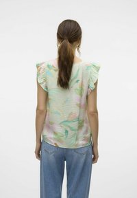 Kraftīgā krāsā ziedu blūze ar īsām volānu piedurknēm, viegls un teksturēts audums, ar pasteļtintēm zaļā, rozā un dzeltenā krāsā.