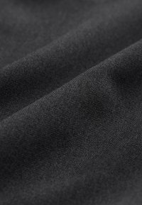 Primo piano di tessuto morbido grigio scuro con trama fine e pieghe delicate che creano ombre sottili.