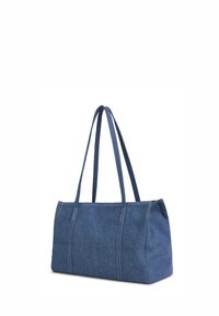 Sac cabas rectangulaire en denim bleu avec doubles poignées longues et coutures visibles sur fond blanc.