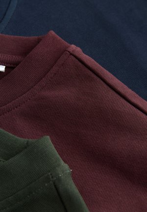 Zbliżenie na trzy koszulki: ciemnoniebieska, bordowa i oliwkowozielona. Posiadają krótkie rękawy, prążkowaną teksturę i staranne szwy.