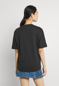 T-shirt nera a maniche corte con colletto rotondo, realizzata in tessuto morbido, abbinata a una mini gonna di jeans. Design semplice e rilassato.