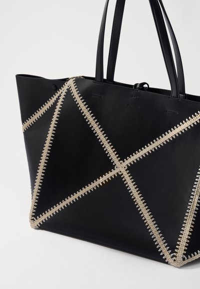 Black leather tote bag featuring a geometric design stitched with beige thread, two sturdy handles, and a smooth texture.
