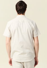 Korte mouwen overhemd in lichtbeige met een geometrisch patroon. Heeft een button-down kraag en een rechte zoom, gemaakt van een zachte stof.