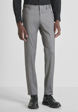 Pantaloni grigi su misura con una texture liscia, caratterizzati da una parte frontale piatta e un motivo sottile, abbinati a scarpe eleganti nere.